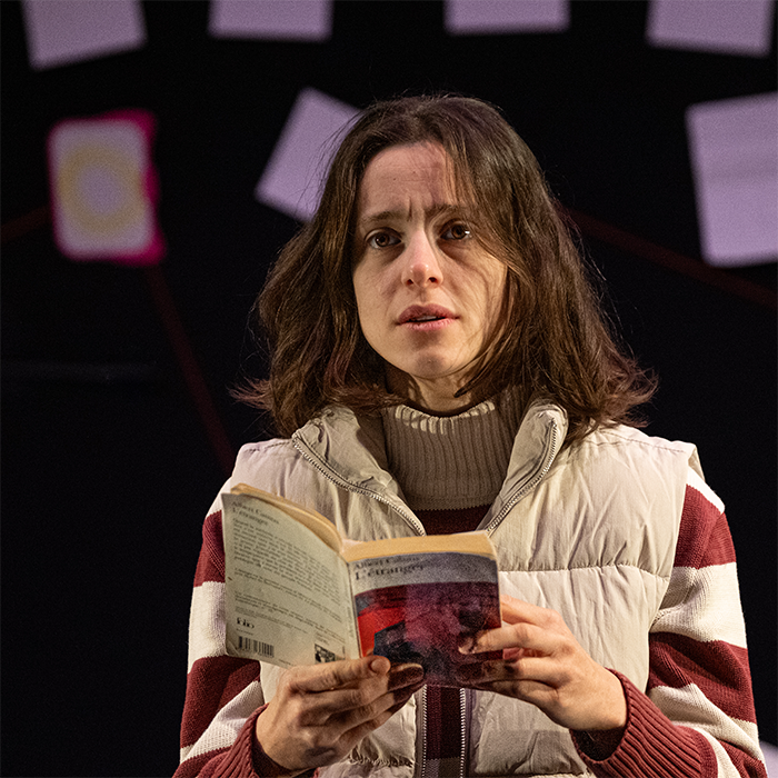 Une femme, un livre à la main, regarde fixement face à elle