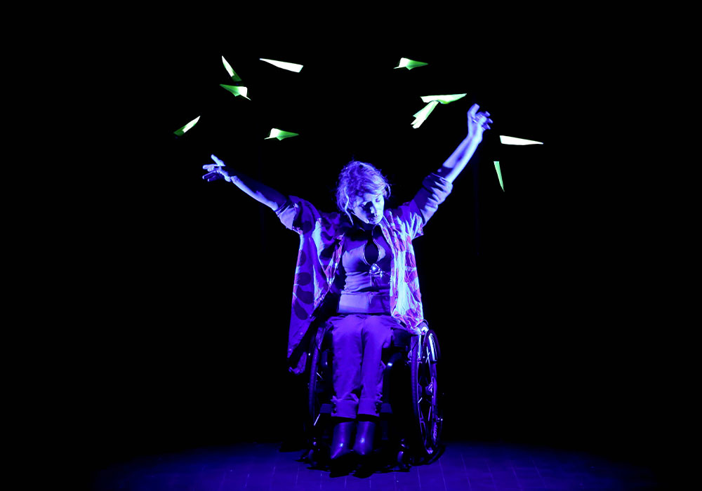 Voltige © Fabienne RAPPENEAU (6) Spectacle Voltige, une femme en fauteuil roulant avec des avions en papier